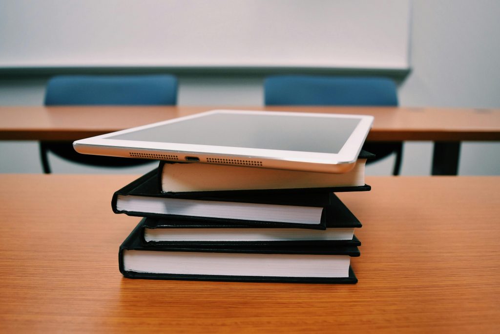 Books with ipad on top, stacked on desk