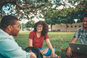 Three people in a circle in the grass representing links